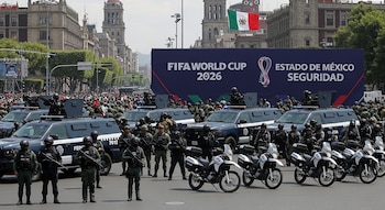 Despliegue de seguridad con policías, militares, vehículos blindados y motocicletas en una calle urbana. Gran cartel "FIFA World Cup 2026 Estado de México Seguridad".