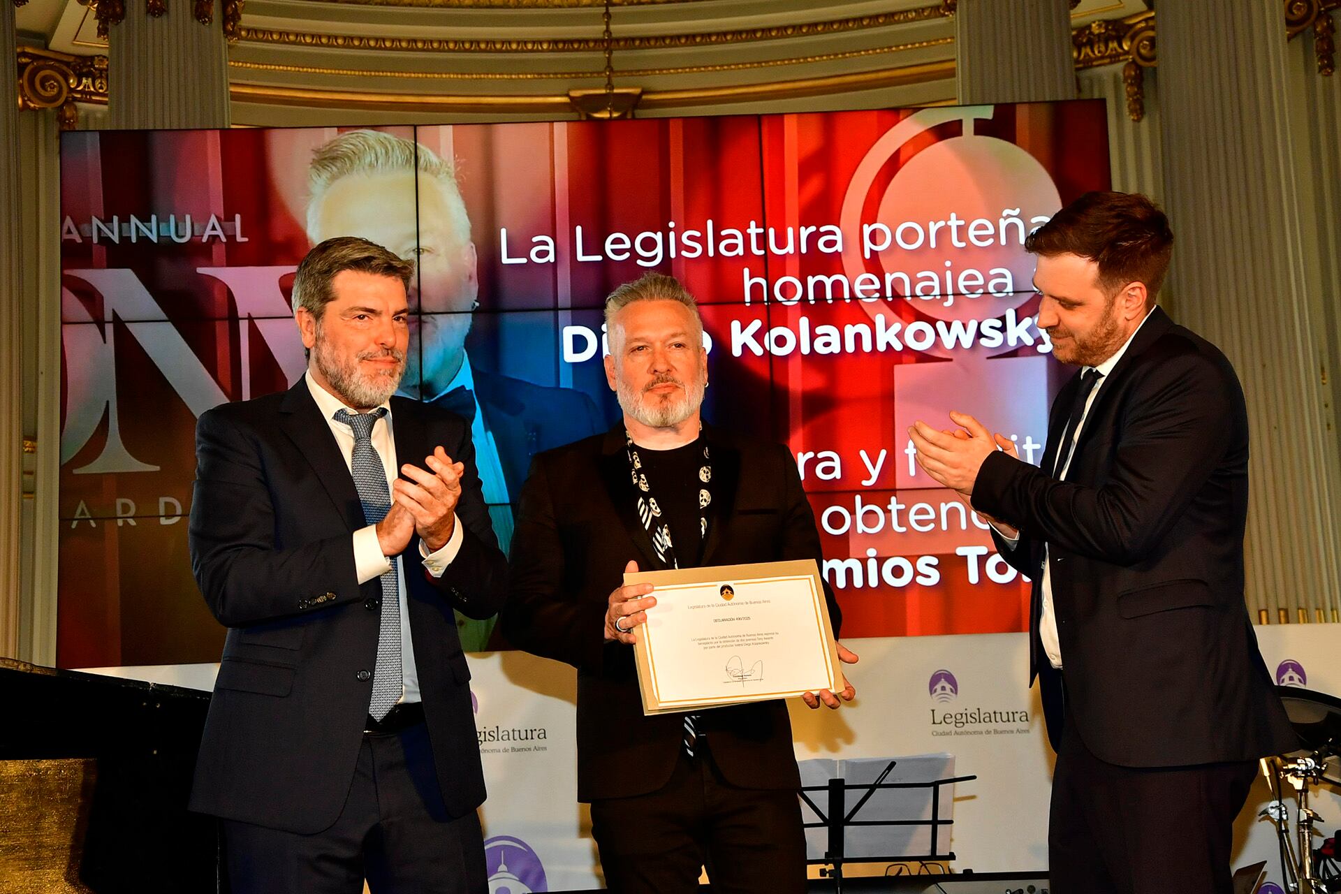 Diego Kolankowsky recibe el Diploma del Homenaje de la Legislatura porteña. Lo rodean el cineasta Gabriel Nesci y el legislador Emmanuel Ferrario
