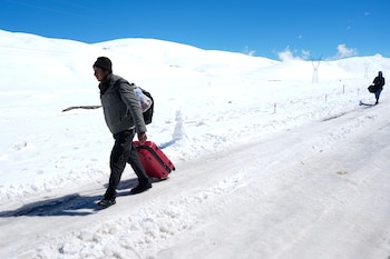 Un hombre camina por una carretera cubierta de nieve tras bajarse de un autobús que no pudo continuar su recorrido debido al mal estado de la carretera en La Cumbre, a las afueras de La Paz (Bolivia), el miércoles 19 de agosto de 2026 (Foto AP/Juan Karita)