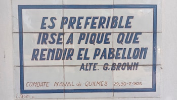 Placa conmemorativa de azulejos blancos y bordes azules que muestra una cita del Almirante G. Brown y la fecha del Combate Naval de Quilmes