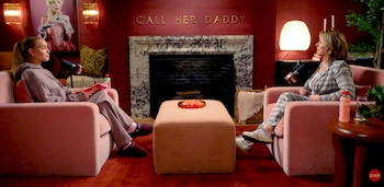 Alexandra Cooper y Kim Kardashian sentadas en sillones rosas, frente a frente, con micrófonos en un estudio de podcast "Call Her Daddy" de color rojo