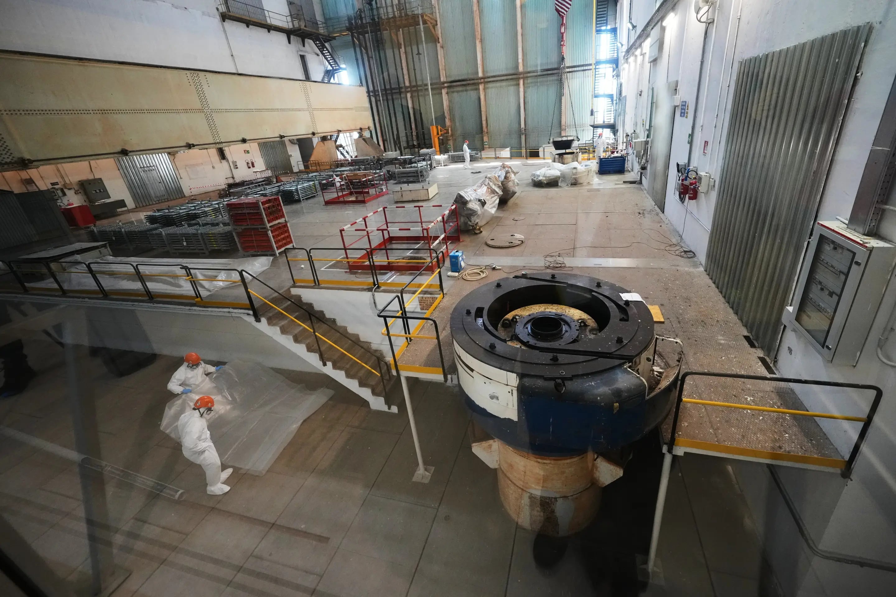 Trabajadores con equipo de protección individual inspeccionan componentes de una instalación de energía nuclear en un amplio espacio industrial. ((Foto AP/Alessandra Tarantino))