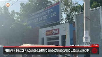 Primer plano de un cartel azul grande que dice 'Municipalidad Distrital Veintiséis de Octubre' sobre un edificio con el letrero 'multiRed'