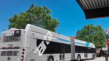 Vista lateral trasera de un autobús articulado gris de MARTA con el número 1708 y ruta 39 bajo un cielo azul. Árboles verdes al fondo y un cartel de STOP