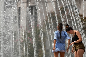 Dos jóvenes se refrescan en una fuente. (EFE/HUGO DELGADO)