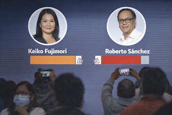 Pantalla mostrando a Keiko Fujimori y Roberto Sánchez con barras de votos. La barra de Fujimori muestra una ligera delantera. Personas con teléfonos en primer plano.