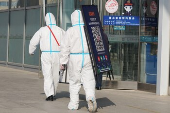 This photo taken on December 8, 2022 shows staff members removing posters for a Covid-19 health code used upon entering the railway station in Xining in China's northwestern Qinghai province. (Photo by CNS / AFP) / China OUT