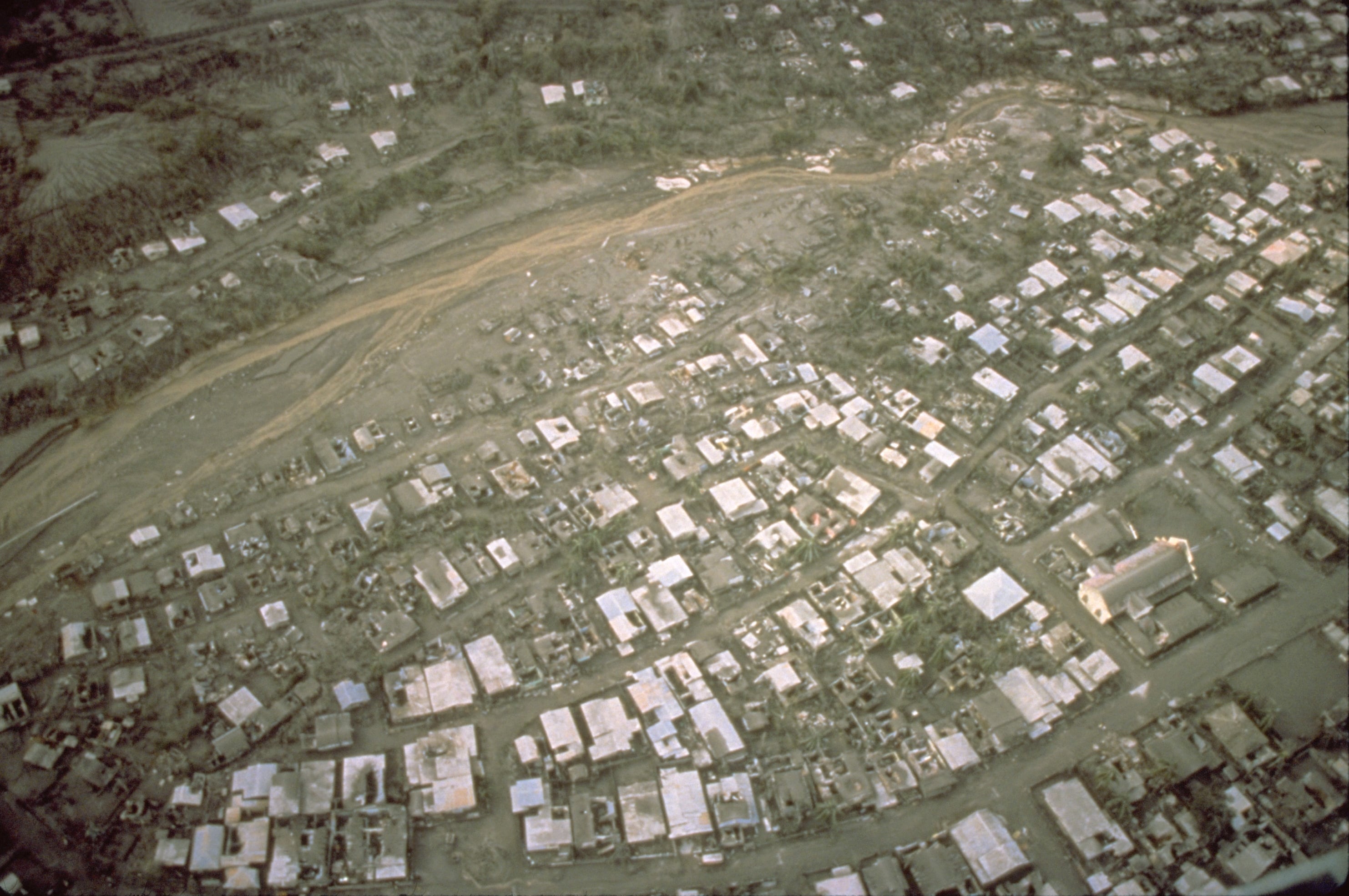 Vista aérea de los daños provocados por lahares y la caída de tefra en techos de Sapangbato, a lo largo del río Abacon, al sur de la base aérea Clark, el 22 de junio de 1991 (Wikipedia)