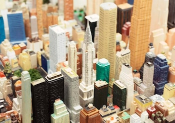 Primer plano de una maqueta de ciudad con numerosos rascacielos y edificios de diferentes colores y tamaños, incluyendo una estructura con una aguja