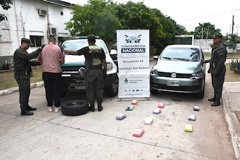 Oficiales de Gendarmería Nacional detienen a un hombre junto a un vehículo policial y un auto compacto verde, con paquetes de droga y un neumático en el suelo