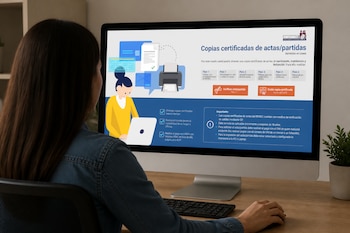 Una mujer de espaldas utiliza una computadora de escritorio que muestra en su pantalla la página de servicios en línea de actas y partidas.