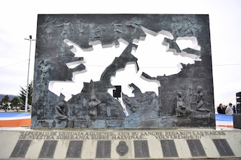 Grupo de personas, incluyendo un veterano de Malvinas con medallas y gorra de la Armada Argentina, y un hombre de chaqueta oscura, parados en un evento al aire libre