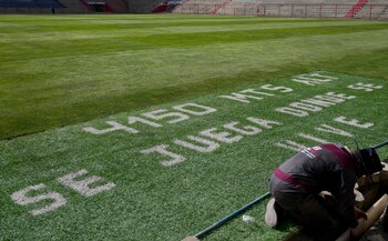 El terreno de juego del estadio municipal Villa Ingenio tiene una parte con un mensaje que dice que está a 4.150 metros sobre el nivel del mar y que "se juega donde se vive", en El Alto, Bolivia, el jueves 29 de agosto de 2024. (AP Foto/Juan Karita)