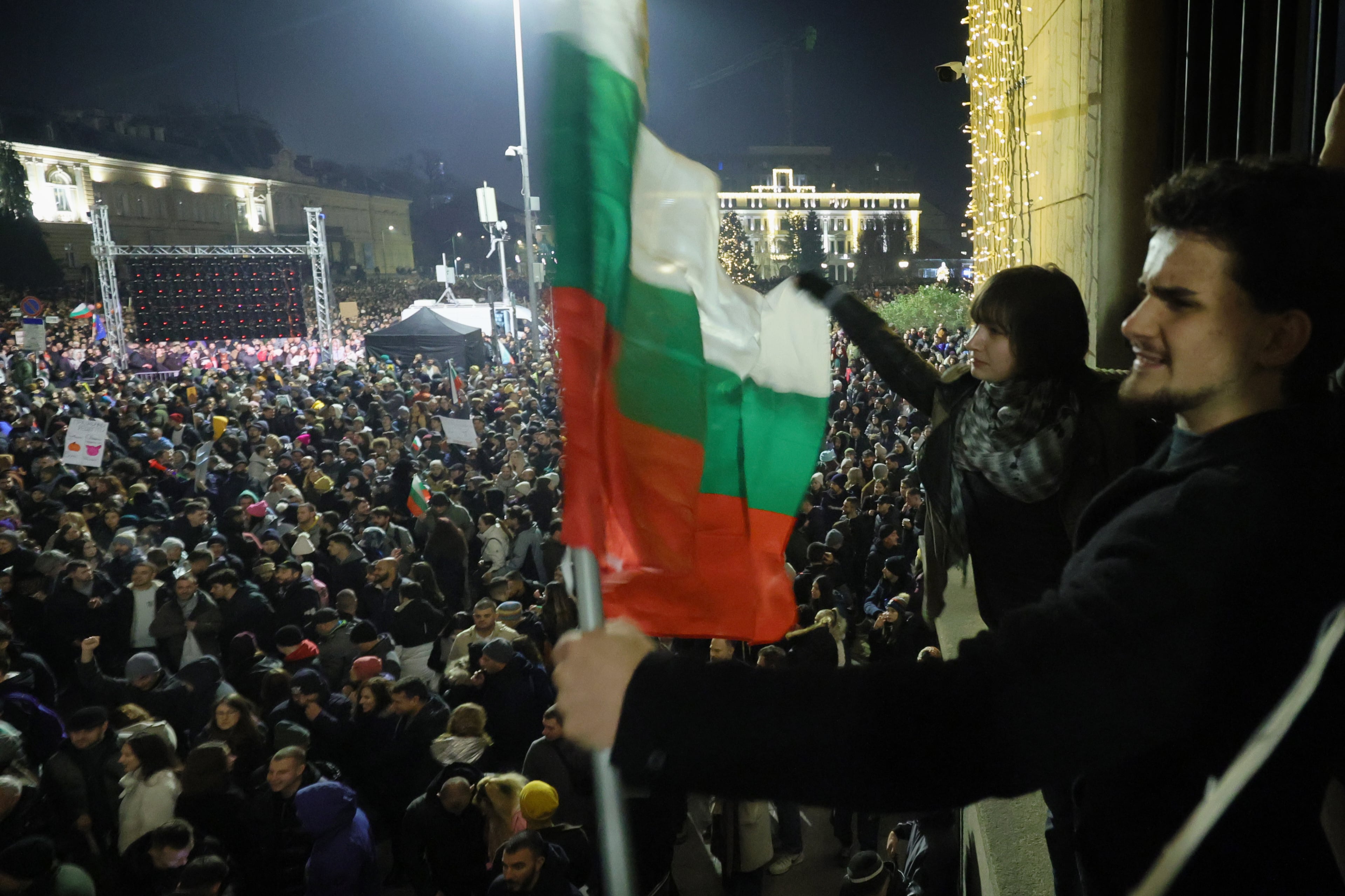 Estudiantes ondean la bandera búlgara mientras decenas de miles de personas llenan la plaza central de Sofía, exigiendo la dimisión del gobierno en medio de la creciente indignación por la corrupción y las controvertidas políticas económicas, el miércoles 10 de diciembre de 2025, en Sofía, Bulgaria. (AP Foto/Valentina Petrova)
