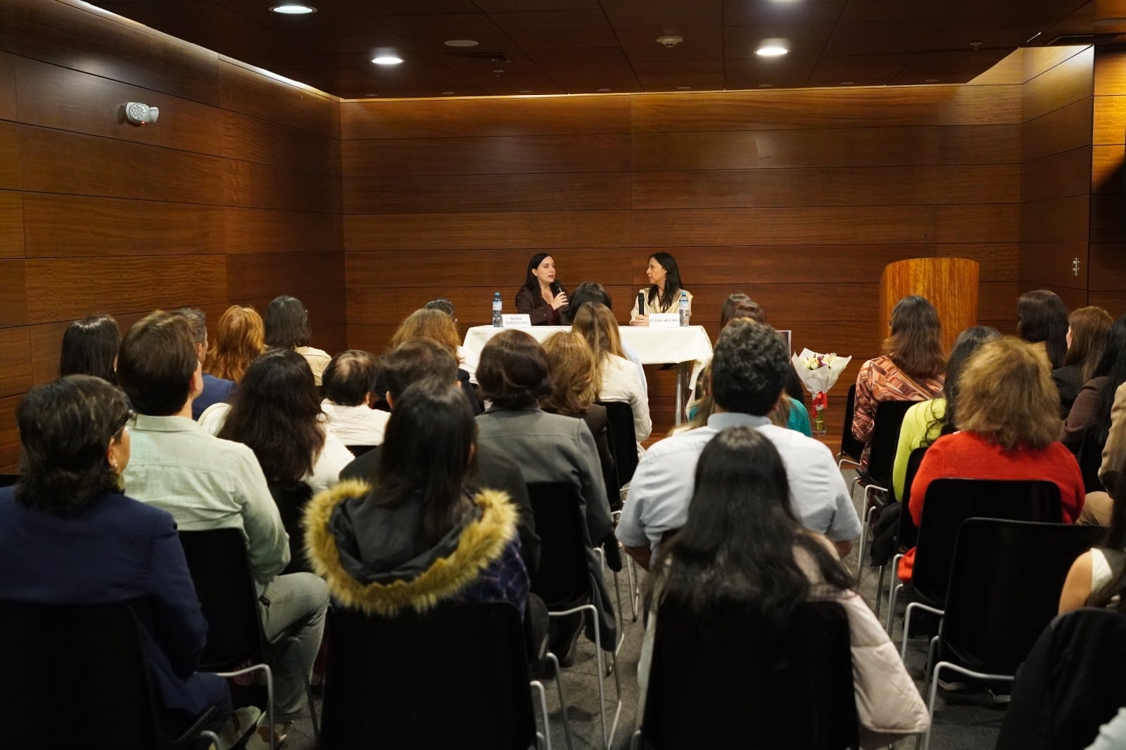 Dos ponentes se dirigen a un público sentado desde una mesa principal durante una presentación formal. (Durante años, Elena Molina Vivanco buscó una respuesta para síntomas que no encontraban nombre en ningún diagnóstico: migrañas, fatiga, problemas digestivos e intolerancias alimentarias que se acumulaban sin que los análisis clínicos ofrecieran una explicación. Esa búsqueda, larga e incierta, se convirtió en el punto de partida de El grito silencioso del cuerpo, su primer libro, publicado con Editorial Planeta Perú, con el que la comunicadora busca visibilizar en el país la histaminosis por déficit de DAO, una condición médica que puede permanecer sin identificar durante años en personas con síntomas persistentes.)