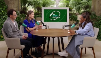 Tres personas sentadas alrededor de una mesa redonda con micrófonos frente a una pantalla con el logo 'The Oprah Podcast' en un estudio con vegetación
