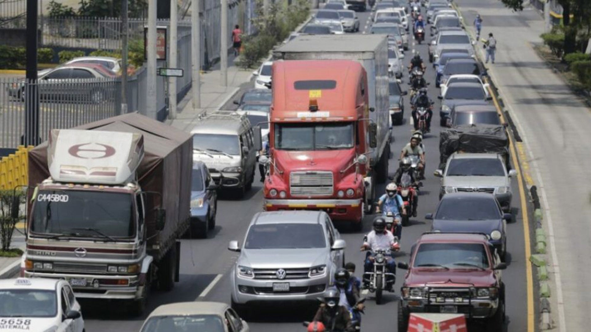 La imagen muestra un día de tráfico intenso con una fila interminable de coches, camiones y motocicletas atascados en una calle urbana principal, evidenciando los desafíos de la movilidad en la ciudad. (Agencias de Gobierno)