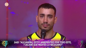Un hombre de piel morena con barba, Said Palao, habla frente a un micrófono en un estudio de televisión. Viste una camiseta deportiva de color neón amarillo y azul