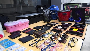 Mesa de madera con objetos perdidos: celulares, billeteras, gafas, mochilas, un laptop, olla arrocera y documentos de identidad