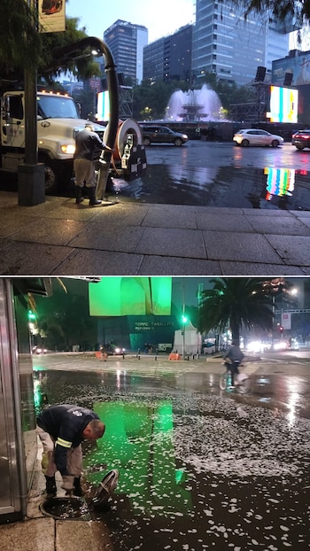 Dois trabalhadores em uma rua inundada. Caminhão aspirador com mangueira, operador próximo ao bueiro com tampa. Espuma de espuma, edifícios, carros