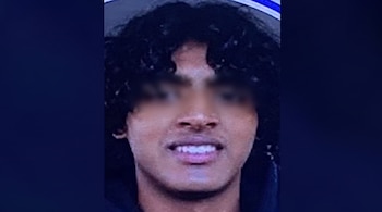 Primer plano de un rostro humano con cabello oscuro y rizado. La persona sonríe mostrando los dientes blancos. Los ojos están borrosos.