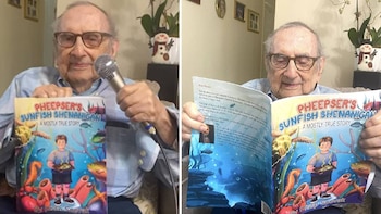 Un hombre mayor sonriente con gafas y camisa a rayas azules sostiene un libro infantil vibrante y un micrófono, mostrando la portada con un niño en un arrecife