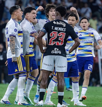 Cinco futbolistas con uniforme blanco y azul festejan de pie frente a un jugador de espaldas con camiseta negra y el dorsal 23