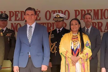 Elizabeth García, embajadora de Colombia, en un atuendo amarillo tradicional, junto a Rodrigo Paz en traje azul, flanqueados por militares y otras personas en un evento