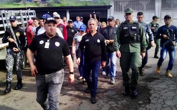 Un grupo de hombres, incluyendo a Freddy Bernal y Miguel Domínguez, con algunos en uniforme militar y otros de civil, caminan por una calle agrietada