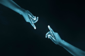 Dos manos en un tono azul brillante apuntan una hacia la otra. Las puntas de los dedos emiten un resplandor más intenso sobre un fondo negro