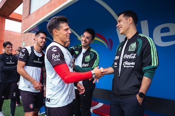 Rafael Márquez estrecha la mano de un futbolista del Club Atlas en un banquillo de entrenamiento junto a otros integrantes del equipo