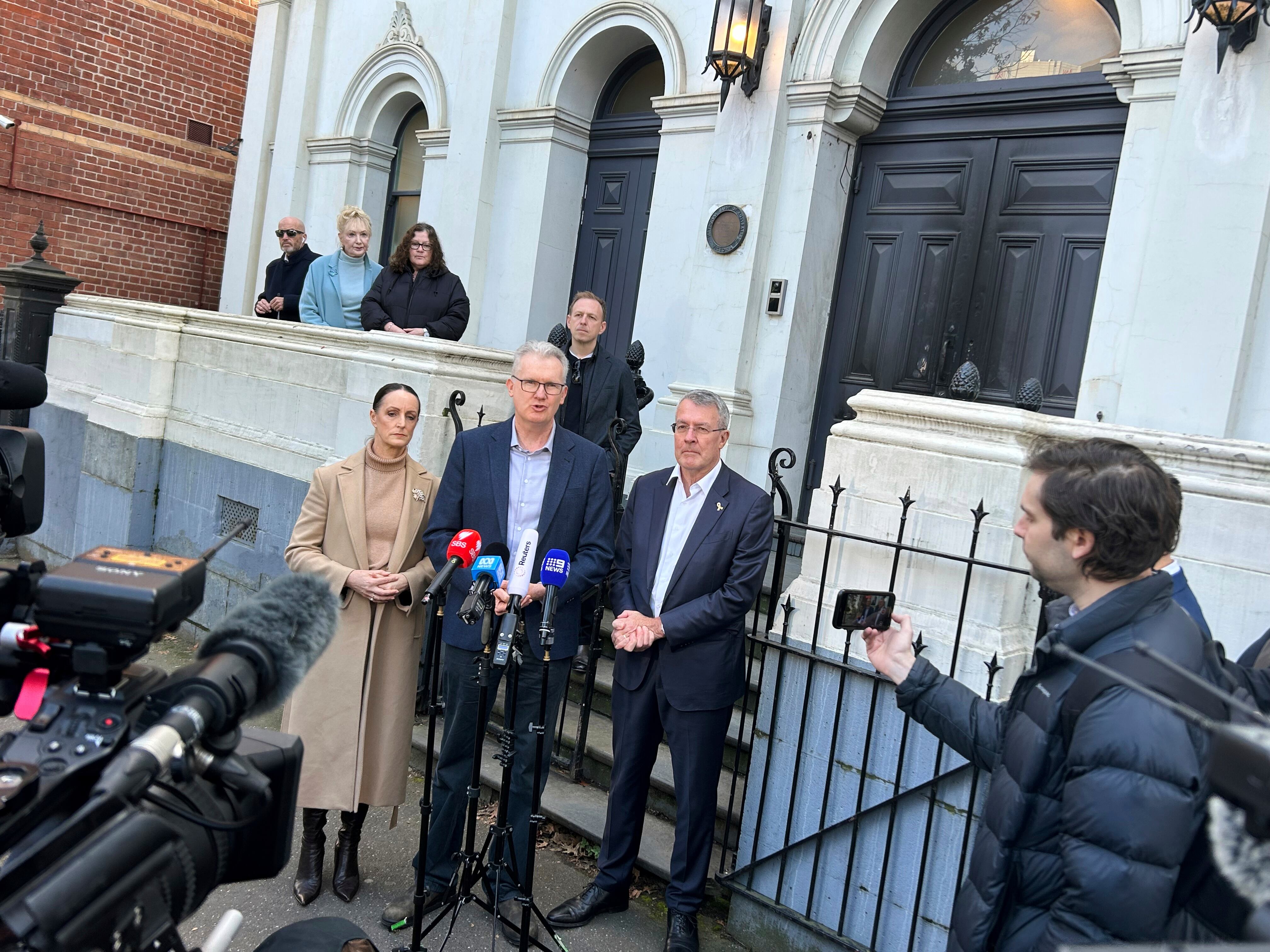 La legisladora del gobierno australiano Sarah Witty, en el centro a la izquierda; el ministro del Interior Tony Burke, en el centro, y el legislador judío Mark Dreyfus, en el centro a la derecha, se dirigen a los medios ante la Sinagoga de Melbourne Este en Melbourne, Australia, el domingo 6 de julio de 2025, después de que alguien prendiera fuego a la puerta delantera de la sinagoga dos días antes. (AP Foto/Rod McGuirk)