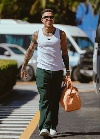 En días cálidos, opta por una musculosa blanca y pantalón deportivo verde, sumando cadenas y bolsos de lona naranja con monograma