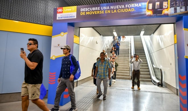Personas acceden a una estación de la Línea 2 del metro de Perú, con escaleras, una cinta transportadora y cartelería informativa sobre el servicio. (ATU)