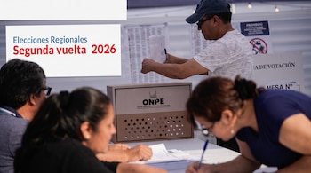 Personas reunidas ante una mesa con una caja electoral de la ONPE y un cartel sobre las elecciones regionales de 2026.