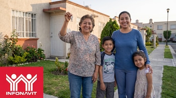 Mujer mayor con llaves de casa, hija y dos niños sonrientes frente a una vivienda en México. Se observa el logo de Infonavit en la esquina inferior izquierda.