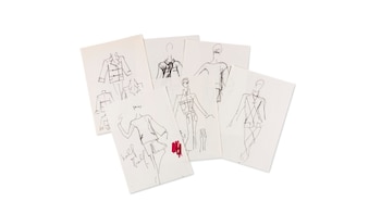 Varias hojas de papel blanco sobre una superficie clara contienen bocetos de moda a línea en tinta negra con algunos trazos rojos