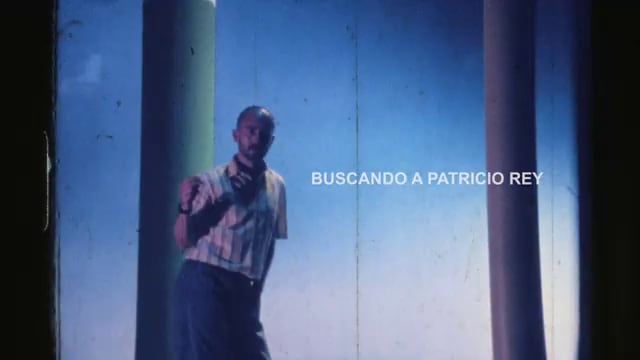 El cantante Indio Solari permanece de pie entre dos columnas con el texto «Buscando a Patricio Rey».