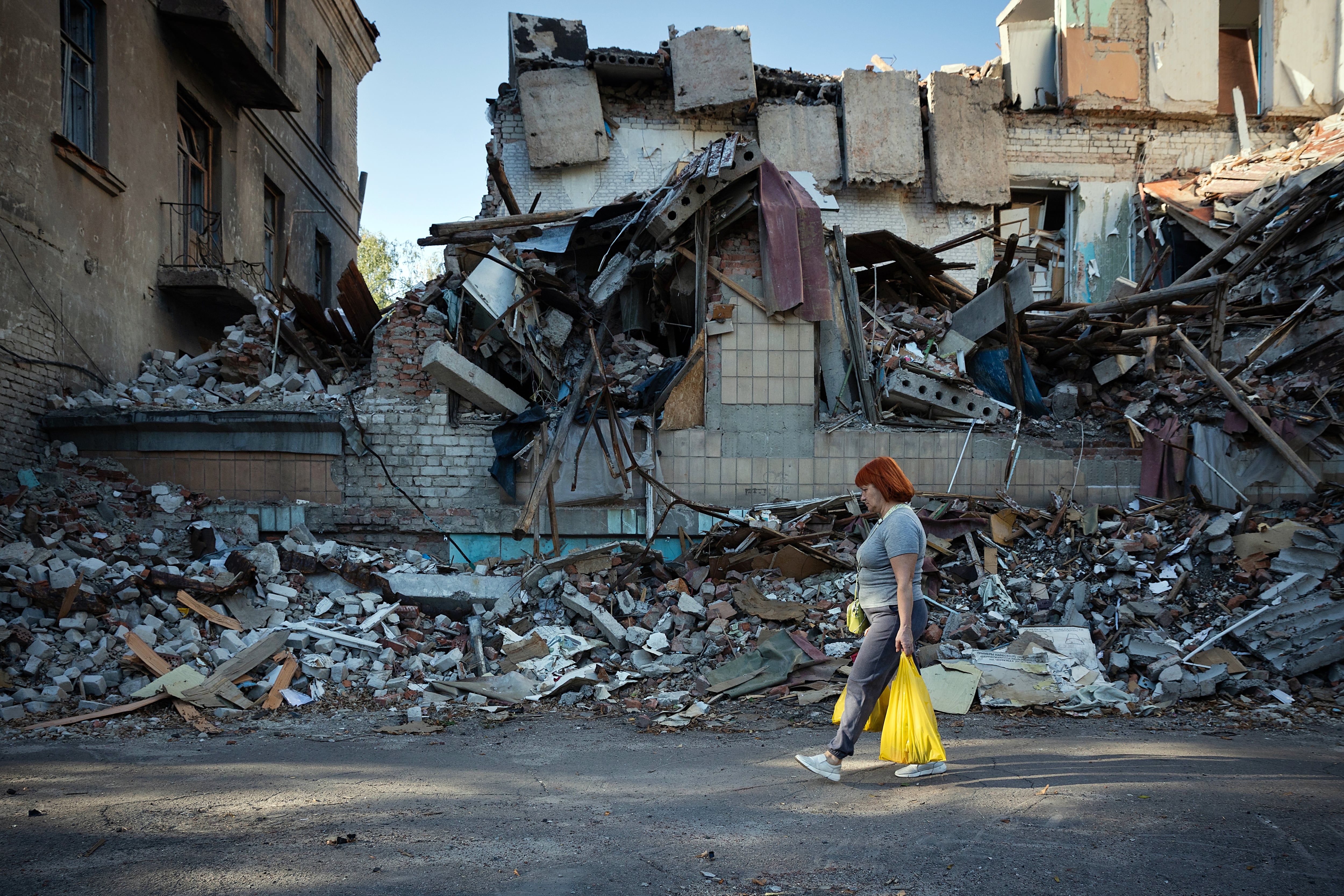 FILE — A woman walks past the wreckage of destroyed buildings in Sloviansk, in the Donbas region of Ukraine, on Sept. 14, 2025. Moscow says its capture of the region is inevitable. But Kyiv has so far stymied Russian efforts to encircle Ukrainian “fortress belt” cities. (Tyler Hicks/The New York Times)