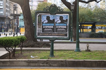 Un soporte publicitario metálico con dos afiches con el lema Organizar la esperanza y la silueta de un orador en un entorno urbano