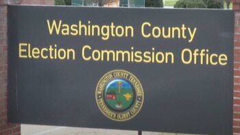 Un letrero oscuro con letras amarillas que dice "Washington County Election Commission Office" y un sello circular debajo
