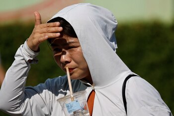 Una persona con protección solar utiliza su mano para protegerse del sol, en medio de una ola de calor en una calle de Beijing, China 30 de junio 2023. REUTERS/Tingshu Wang/Archivo