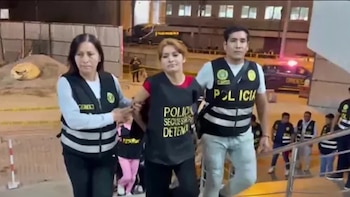 Crismar Andreína Contreras Gonzales, alias 'La Cortadedos', es custodiada por dos agentes policiales en chalecos reflectantes. Se observa una escalera y otros oficiales al fondo