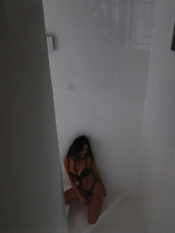 Zaira Nara posa arrodillada en un espacio blanco minimalista, vestida con un conjunto de lencería negra de dos piezas