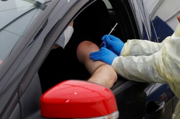 A health worker vaccinates a person with a dose of coronavirus disease (COVID-19) vaccine at the first drive-in vaccination center in Berlin, Germany, February 10, 2022. REUTERS/Michele Tantussi