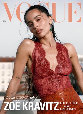 La actriz Zoë Kravitz en la portada de Vogue, con un top de encaje rojo, aretes verdes y cabello recogido, frente a un cielo claro