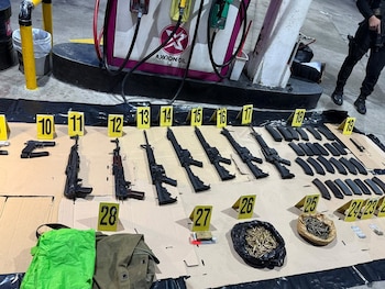 Cuatro agentes policiales caminan por una calle junto a dos hombres esposados que tienen el rostro difuminado