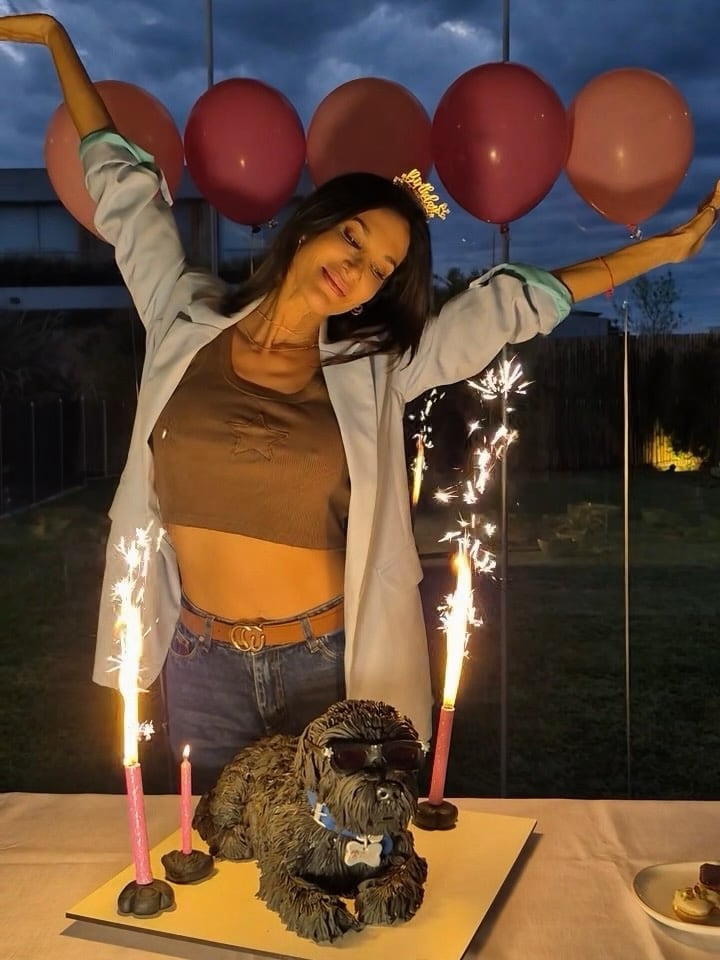 Silvina Escudero posa en la celebración de su cumpleaños junto a un pastel diseñado con la figura de su perro Titán y velas de chispas.