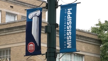 Dos pancartas azules en un poste, una con el dibujo de una columna y otra con la inscripción The University of Mississippi