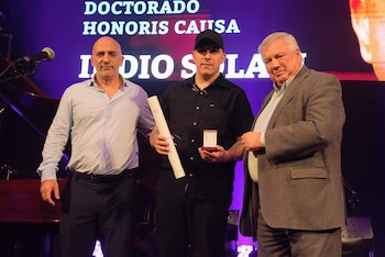 El vicerrector de la UBA Emiliano Yacobitti y el rector Ricardo Gelpi le entregaron a Gaspar Benegas la distinción para el Indio Solari